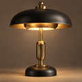 Art Deco mushroom dome table lamp full product view - wide matte black dome shade with brushed gold interior, solid brass fluted column, polished brass finial ball top, weighted black disc base, warm amber glow, neutral background